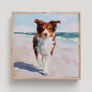 May include: A framed painting of a dog running on a beach. The dog has brown and white fur and is facing the viewer. The background shows the ocean and sky in shades of blue and white. The painting is in a square wooden frame.