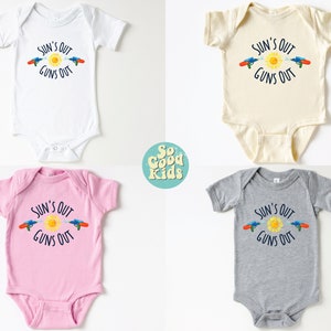 May include: Four baby onesies in white, cream, pink, and gray, each with the text "SUN'S OUT GUNS OUT" and a graphic of a sun and water guns. The onesies are short-sleeved.