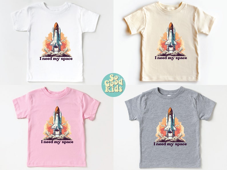 K&ouml;nnte beinhalten: Vier T-Shirts in Kindergr&ouml;&szlig;e in Wei&szlig;, Beige, Rosa und Grau mit einer Grafik eines startenden Raumschiffs. Der Text "Ich brauche meinen Platz" ist unter der Grafik gedruckt.