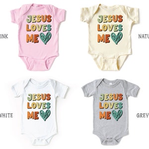 Puede incluir: Cuatro bodies de beb&eacute; en rosa, blanco, natural y gris con el texto "Jes&uacute;s me ama" en colores arco&iacute;ris y un coraz&oacute;n verde.