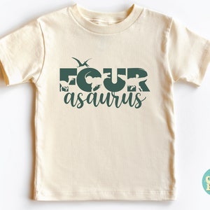 May include: A light beige t-shirt with a green graphic that says "FOURasaurus" with dinosaur silhouettes incorporated into the letters.