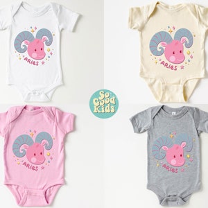 May include: Four baby onesies with different coloured backgrounds. Each onesie features a pink cartoon ram with blue horns and the word "Aries" printed below. The onesies are white, cream, pink, and grey.