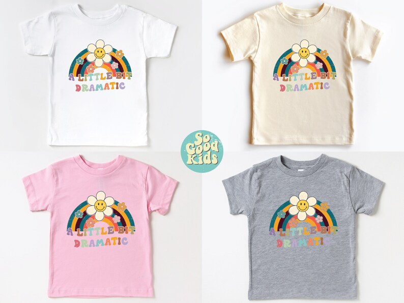 Pode incluir: Quatro camisetas para crian&ccedil;as pequenas em diferentes cores com um arco-&iacute;ris e uma margarida com um rosto sorridente. O texto nas camisetas diz "A Little Bit Dramatic".