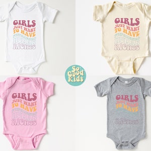 May include: Four baby onesies in different colors, white, cream, pink, and gray. Each onesie has the text "Girls Just Want To Have Human Rights" printed in a rainbow color scheme.
