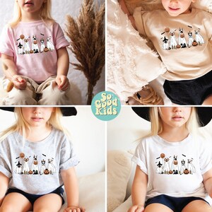 Puede incluir: Cuatro ni&ntilde;os visten camisetas de diferentes colores con un gr&aacute;fico de perros disfrazados con trajes de Halloween. El texto "So Good Kids" est&aacute; en el centro de la imagen.