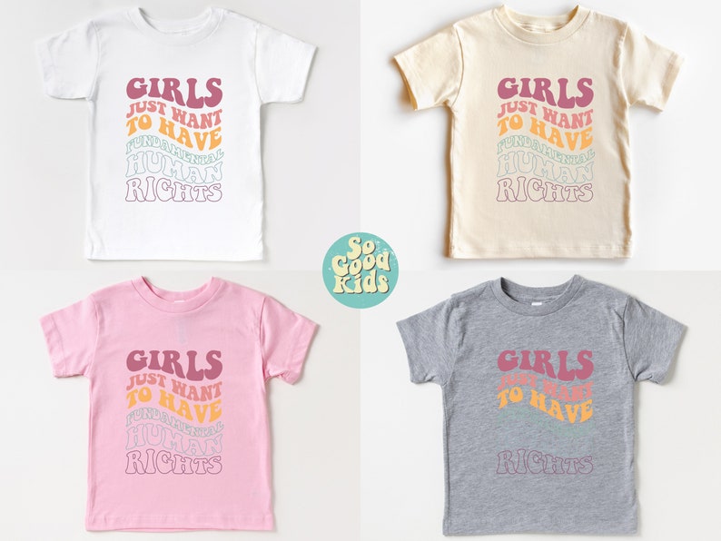 May include: Four toddler-sized t-shirts in white, beige, pink, and gray with the text "Girls Just Want To Have Fundamental Human Rights" in a retro font with a rainbow color scheme.