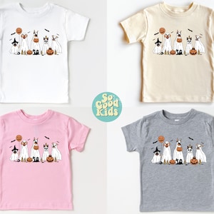 Puede incluir: Cuatro camisetas de tama&ntilde;o para ni&ntilde;os peque&ntilde;os con un gr&aacute;fico de Halloween de perros disfrazados de fantasmas. Las camisetas son de color blanco, beige, rosa y gris.