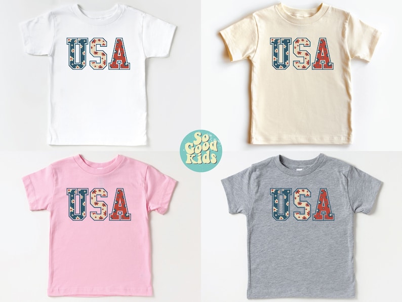 K&ouml;nnte beinhalten: Vier T-Shirts in Kindergr&ouml;&szlig;e mit dem Wort "USA" auf der Vorderseite. Die Shirts sind in Wei&szlig;, Beige, Rosa und Grau. Die Buchstaben bestehen aus einem roten, wei&szlig;en und blauen Blumenmuster.