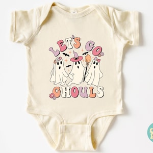 May include: A cream-colored baby onesie with a graphic of three ghosts wearing witch hats and flowers. The text "Let's Go Ghouls" is written in pink, orange, and blue letters.