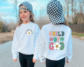 May include: Two white sweatshirts with a graphic design of a flower with a smiley face. The text on the sweatshirts reads "Child of God".