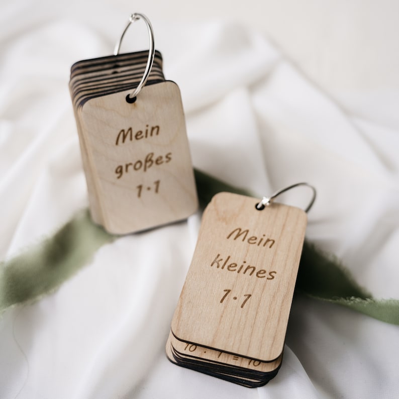 K&ouml;nnte beinhalten: Zwei S&auml;tze Holz-Karteikarten mit silbernen Ringen. Der obere Satz sagt "Mein gro&szlig;es 1-1" und der untere Satz sagt "Mein kleines 7-7".