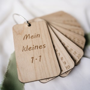K&ouml;nnte beinhalten: Holzkarten mit Zahlen und einem Ring zum einfachen Aufbewahren. Die oberste Karte zeigt "Mein kleines 7-7".