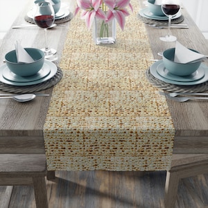 May include: A beige and brown patterned table runner is centered on a wooden table, set for a meal. The table is set with blue bowls, white plates, silverware, and wine glasses. A vase of pink lilies sits in the center.