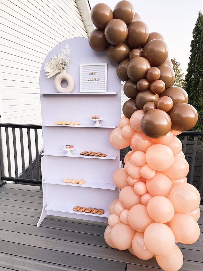 A beautifully designed arched party backdrop featuring built-in shelves, perfect for showcasing decorations, party favors, or other items at events and gatherings. Ideal for creating a stylish and functional display at any celebration.