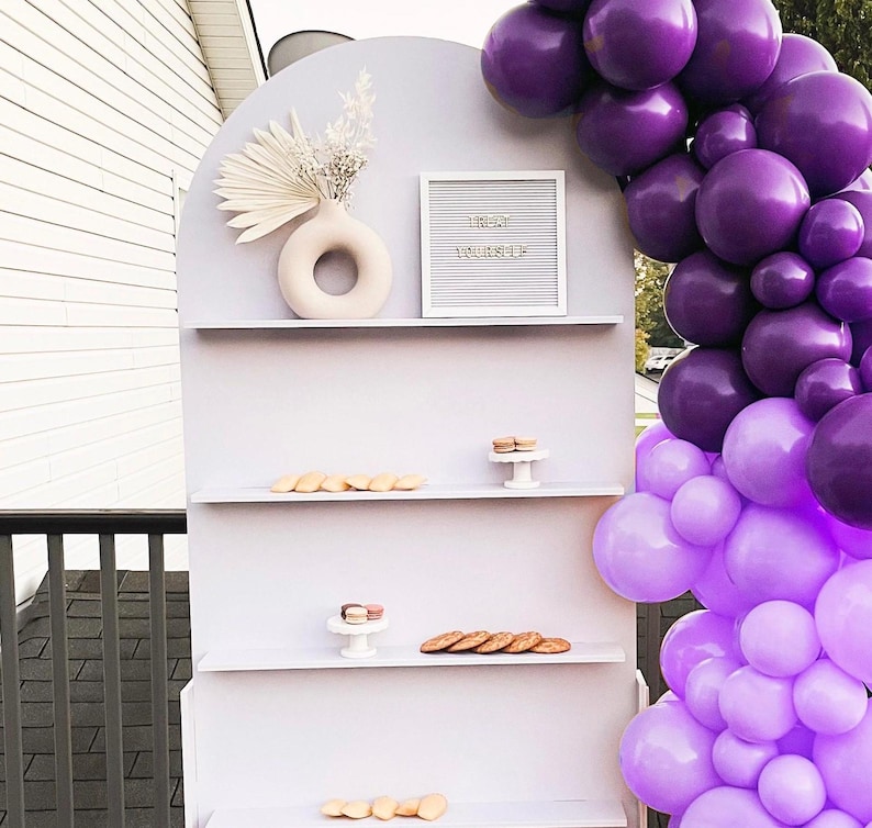 A beautifully designed arched party backdrop featuring built-in shelves, perfect for showcasing decorations, party favors, or other items at events and gatherings. Ideal for creating a stylish and functional display at any celebration.