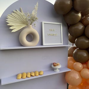A beautifully designed arched party backdrop featuring built-in shelves, perfect for showcasing decorations, party favors, or other items at events and gatherings. Ideal for creating a stylish and functional display at any celebration.