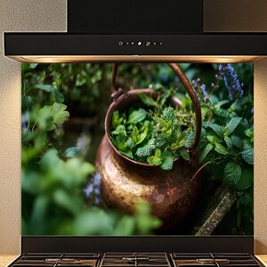 May include: A copper-colored pot filled with fresh green herbs, set against a backdrop of lush greenery. The pot is suspended by a handle, creating a rustic and natural aesthetic. The image is a kitchen backsplash.
