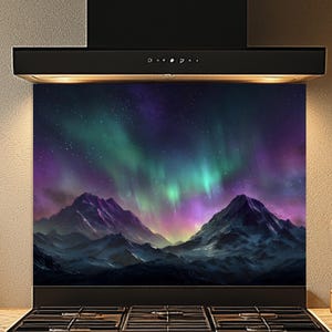 Könnte beinhalten: Dunstabzugshaube mit einem lebendigen Bild der Aurora Borealis über einer Bergkette. Das Kunstwerk zeigt Farbtöne von Lila, Grün und Blau. Der Herd ist schwarz mit mehreren Brennern und Bedienknöpfen.