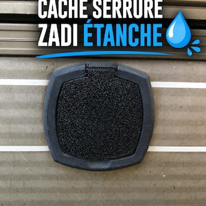 Può includere: Una copertura per serratura nera e strutturata con forma rettangolare arrotondata. La copertura è montata su una superficie marrone chiaro con linee orizzontali. Il testo "CACHE SERRURE ZADI ÉTANCHE" è visualizzato in bianco e blu.