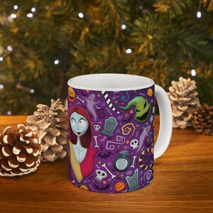 May include: White ceramic mug with a purple background, decorated with Halloween-themed illustrations. The design includes Sally from The Nightmare Before Christmas, ghosts, tombstones, and Jack Skellington's face. The mug has a white handle.