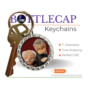 May include: A silver bottle cap keychain featuring a red background with a photo of two puppets. The puppets are wearing suits and have facial expressions. The text "BOTTLECAP Keychains" is printed in orange and purple letters above the bottle cap.