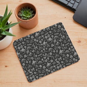 Puede incluir: Alfombrilla de ratón negra con un patrón blanco de varios iconos de parques de Disney y el texto "It's a small world".