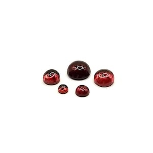 May include: Five red cabochon gemstones of varying sizes. The gemstones are round and have a smooth, polished surface.