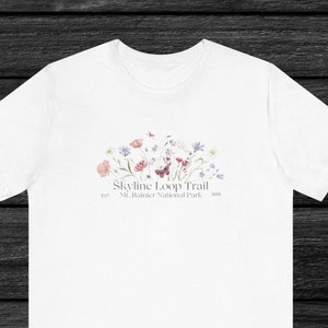 May include: White t-shirt with a floral design and the text "Skyline Loop Trail, Est. 1999, Mt. Rainier National Park" printed on the front.