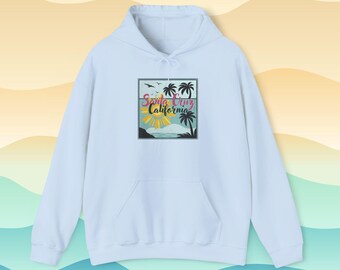 May include: A light blue hoodie with a front pocket and a drawstring hood. The front features a square graphic with the words "Santa Cruz California" in a colorful design, depicting palm trees, the sun, and the ocean.