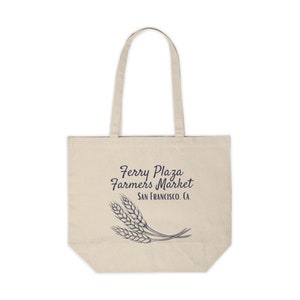 May include: A beige tote bag with the text "Ferry Plaza Farmers Market San Francisco, CA" in dark blue script. Below the text is a dark blue illustration of wheat stalks. The bag has two beige handles.