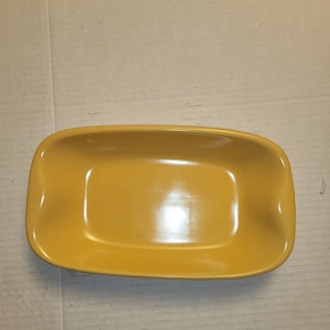 May include: A yellow ceramic rectangular dish with rounded edges. The dish is empty and has a glossy finish.