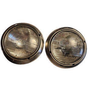 May include: Two round, chrome-plated, automotive headlights with clear glass lenses.