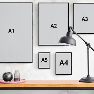 May include: Five black picture frames of different sizes hanging on a white wall. The frames are labeled A1, A2, A3, A4, and A5. A black lamp with a round shade is positioned in front of the frames.