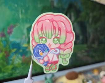 May include: A colorful sticker featuring a cartoon character with pink hair and green highlights, holding a blue character. The sticker has a white border and is set against a blurred background.