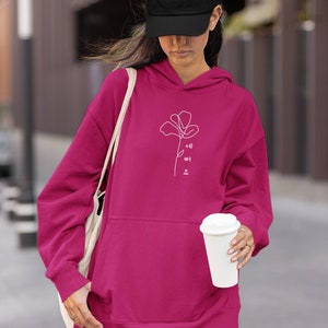 May include: A pink hoodie with a white outline of a flower and the Korean text "예뻐요" which translates to "You are pretty".