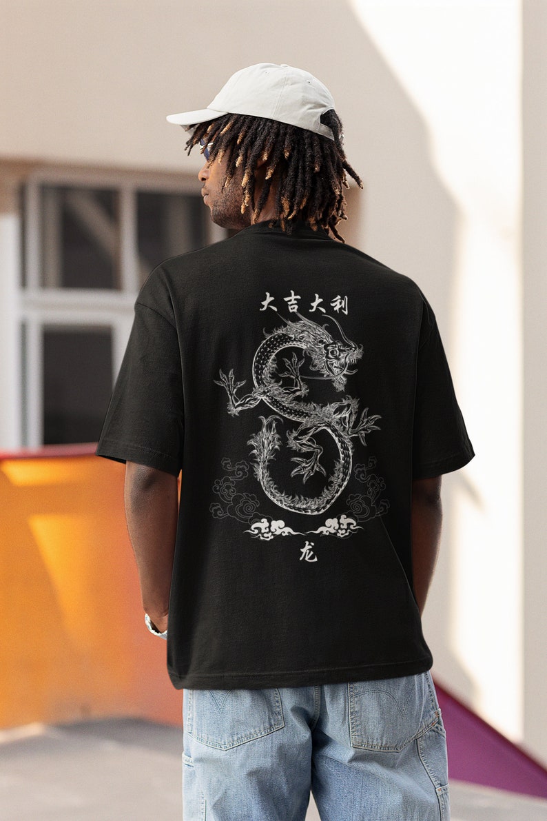 K&ouml;nnte beinhalten: Schwarzes T-Shirt mit einem wei&szlig;en Drachen-Motiv und japanischem Text, der "大吉大利" (ausgesprochen "Dai Kichi Dai Ritsu") lautet und "Gro&szlig;es Gl&uuml;ck, gro&szlig;er Wohlstand" bedeutet.