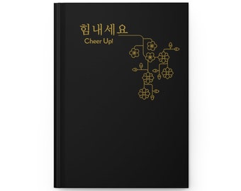 May include: Black notebook with a gold design of a stylized flower branch and the text "힘내세요 Cheer Up!"