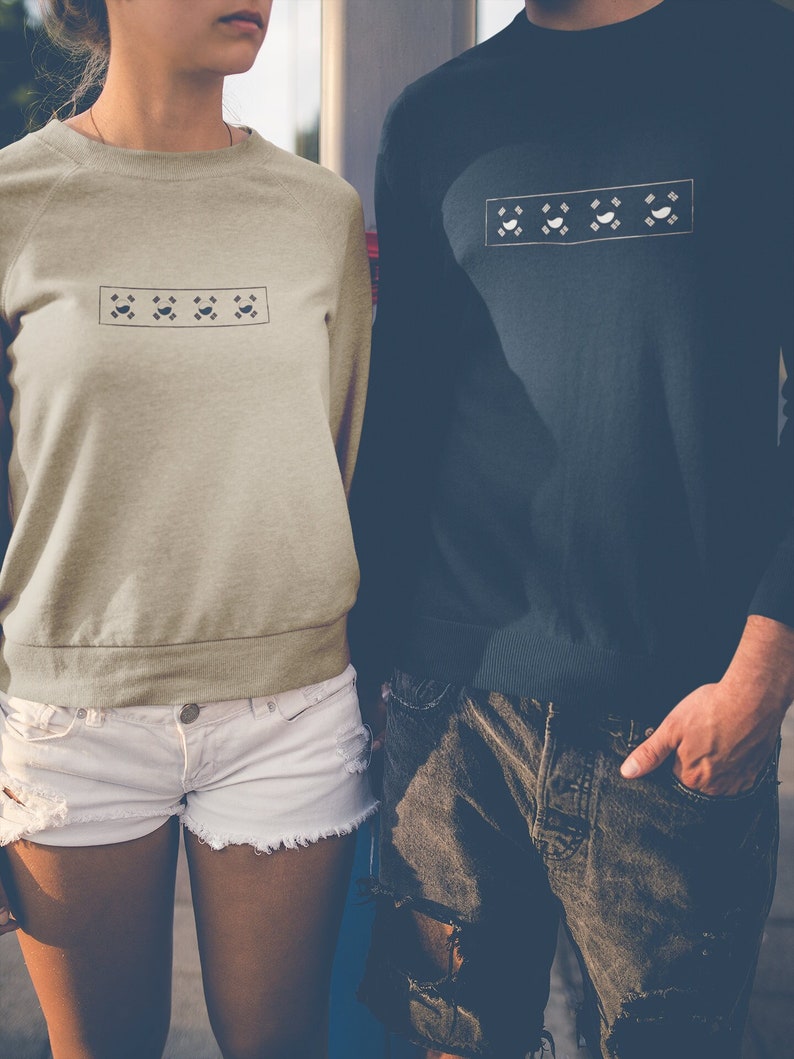 May include: Two people wearing long-sleeved shirts with a geometric pattern on the front. The shirts are in different colors, one is beige and the other is dark blue.