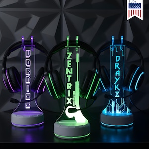 May include: Three illuminated headphone stands with attached headsets. Each stand has a different color scheme: purple, green, and blue. The stands display the names "DORIX", "ZENTRIX", and "DRAYKX". The stands are on a black surface.