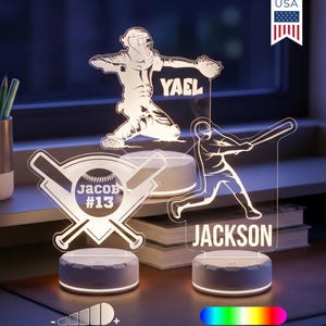 May include: Three custom acrylic LED night lights featuring baseball themes. The designs include a catcher labeled Yael, a batter labeled Jackson, and a baseball with crossed bats labeled Jacob #13. Each light sits on a round white base.