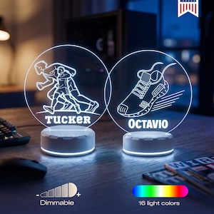 May include: Two personalized LED lamps with white bases. One features a runner graphic and the name "Tucker", the other a running shoe and the name "Octavio". The lamps offer 16 light colors and dimmable settings. "Made in USA" text is visible.