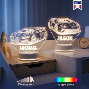 May include: Two custom acrylic LED lamps featuring engraved sports car outlines. One lamp displays the name MICHAEL and the other JASON. Each lamp sits on a round white base with dimmable light settings and 16 color options. A Made in USA badge is visible.