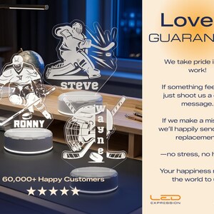 May include: A hockey-themed LED night light with the names "Ronny", "Steve", and "Wayne" etched into the acrylic. The light features hockey player silhouettes and a hockey puck design. The base is a dark gray color. The text "60,000+ Happy Customers" is also visible.