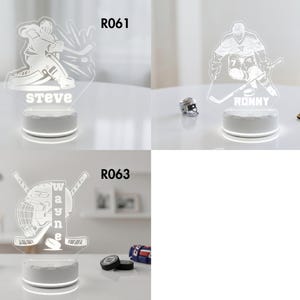 May include: Three illuminated hockey-themed night lights. One features a hockey player with the name "Steve", another with "Ronny", and the third with a helmet, crossed sticks, and the name "Wayne". Each light sits on a white base.
