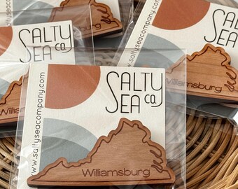 May include: A wooden cutout of the state of Virginia with the text "Williamsburg" and the logo "Salty Sea Co." printed on it. The cutout is packaged in a clear plastic bag.