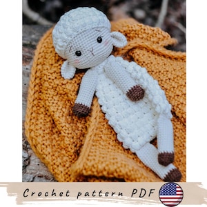 Può includere: Una bambola di agnello bianca all'uncinetto fatta a mano con zoccoli marroni e testa bianca, appoggiata su una coperta di maglia color senape. La bambola ha occhi neri e piccole orecchie. Il testo "Crochet pattern PDF" è in basso.