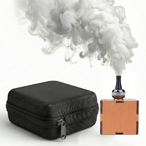 May include: A black zippered case and a small wooden box with a black and silver object on top, emitting white smoke. The smoke billows upwards against a white background, creating a visual contrast.