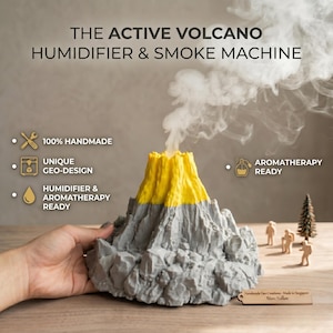 Könnte beinhalten: Ein grau-gelber Vulkan-Luftbefeuchter und Rauchmaschine. Das Produkt ist handgefertigt und verfügt über ein einzigartiges Geo-Design. Es ist aromatherapiebereit und gibt Rauch ab. Der Text auf dem Bild lautet "The Active Volcano Humidifier & Smoke Machine."