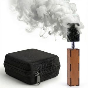 May include: A wooden smoke machine with a black foam head, emitting white smoke. A black zippered case is in the foreground. The smoke billows upwards against a white background. The wooden base is rectangular.