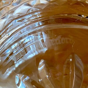 Puede incluir: Primer plano de un objeto de vidrio transparente con un patr&oacute;n de corte de diamante. El vidrio tiene l&iacute;neas curvas y una superficie texturizada. La palabra "tedoro" es visible en el vidrio.